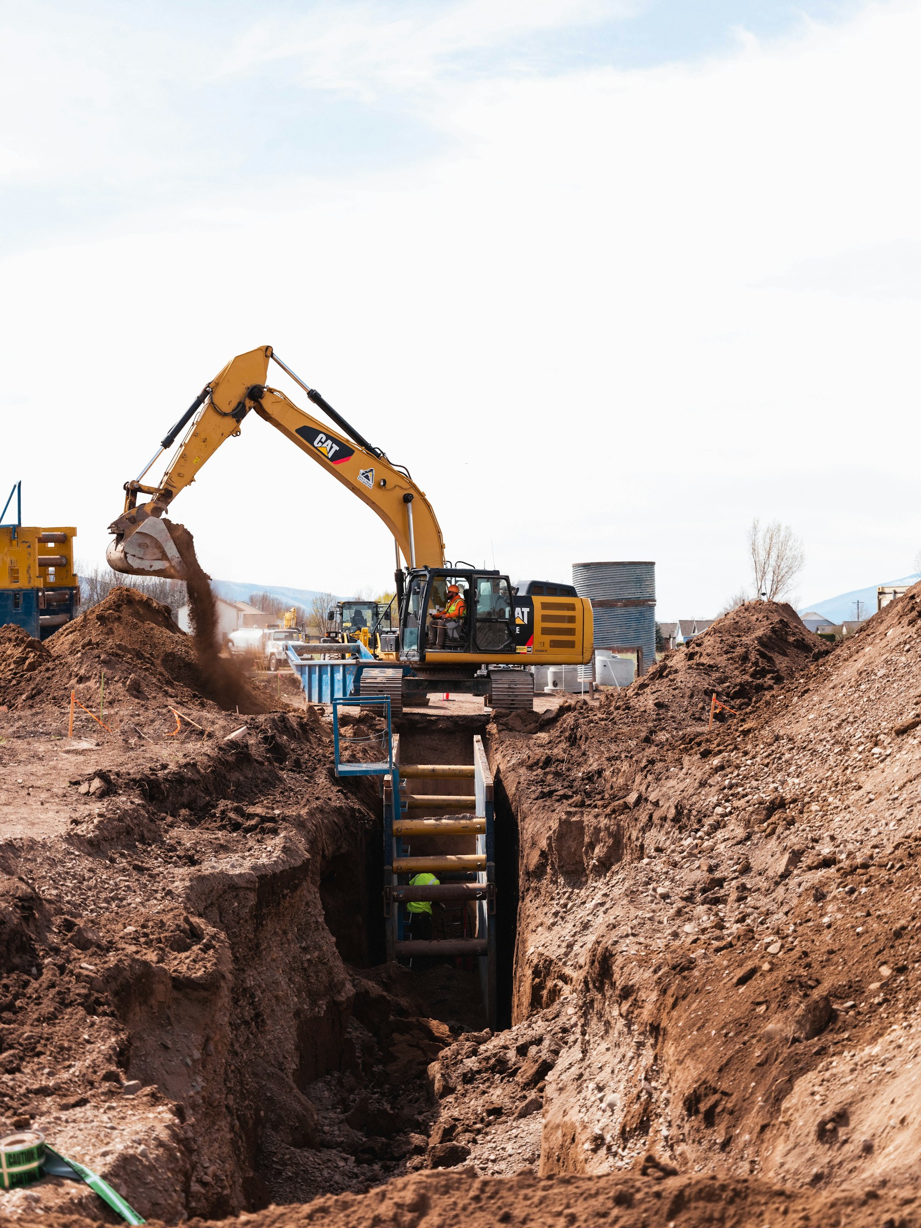 Yellow excavator digging a trench at a construction site
